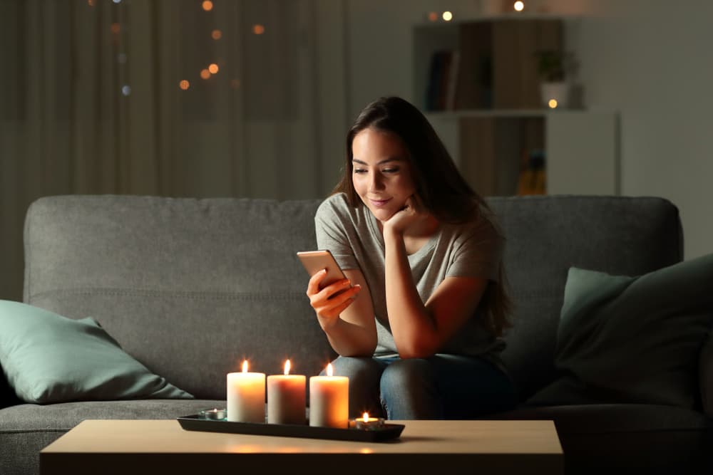 Woman shopping for candles on her phone at home buying pet odor candles