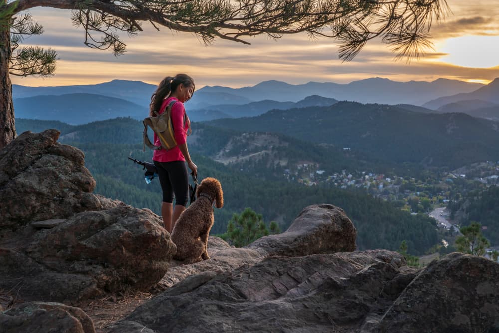 woman with dog hiking on cliff