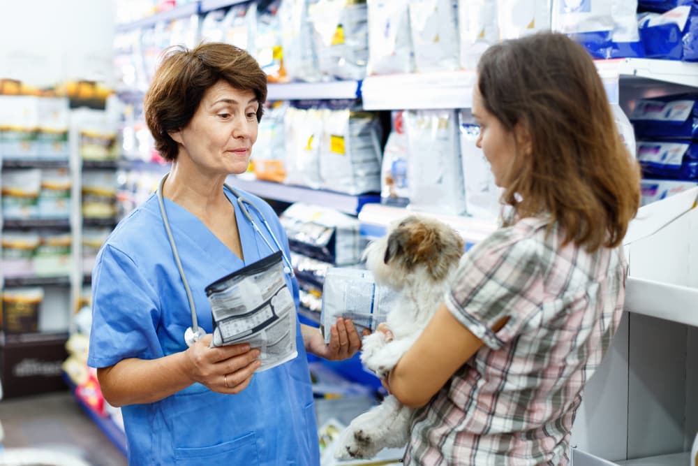 Woman at the shop holding dog talking to vet about dog food