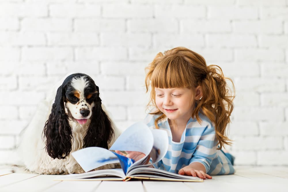Girl reading book to dog