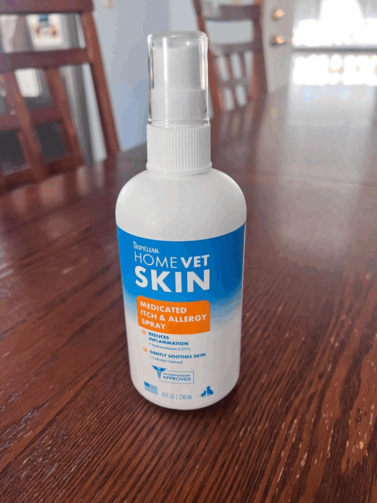 A white bottle of TropiClean HomeVet Medicated Itch and Allergy Spray on a wooden table.