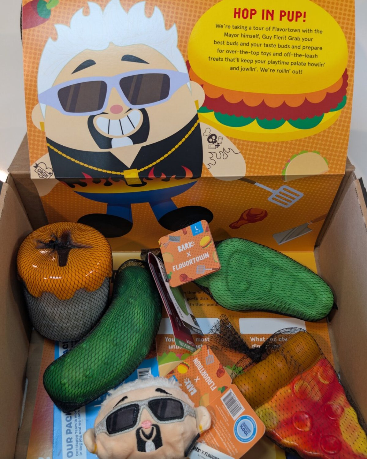 Opened BARK x Flavortown box showing the toys in their mesh sleeves beneath the theme card