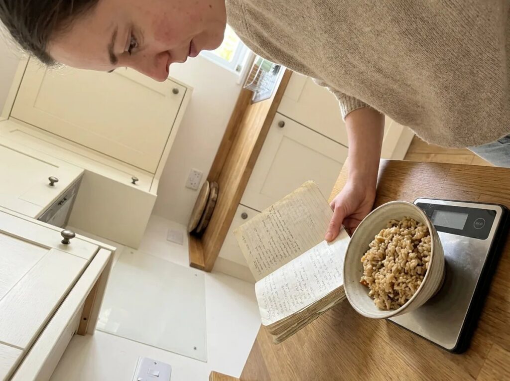 Owner consulting a handwritten notebook beside a small food bowl on a scale.
